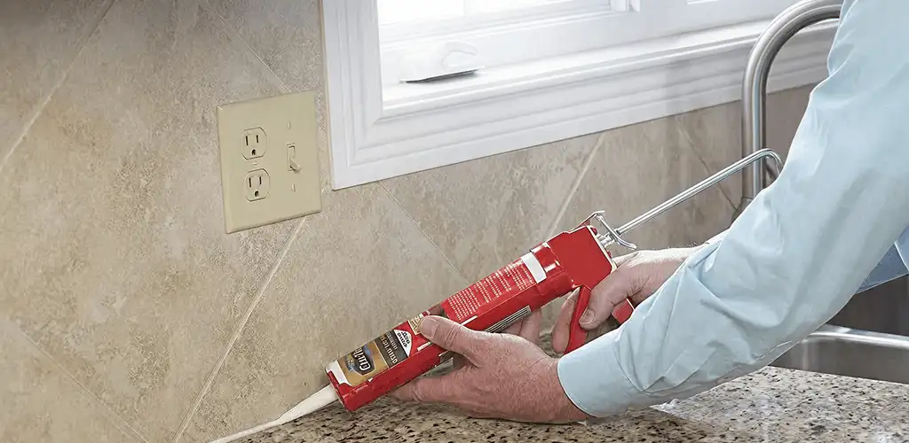 Handyman applying caulk along a kitchen backsplash and countertop seam in Stockton, CA