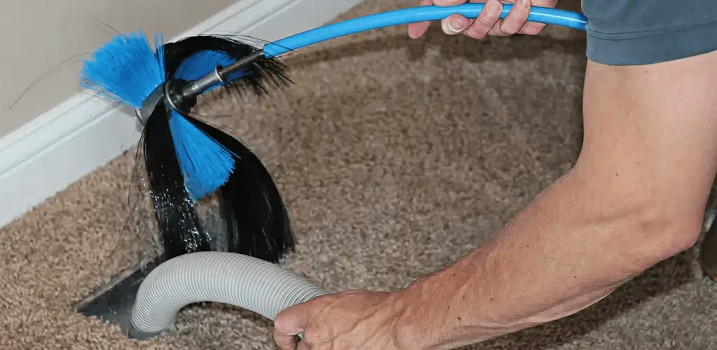 Dryer vent cleaning technician brushing lint from a vent line in Stockton, CA