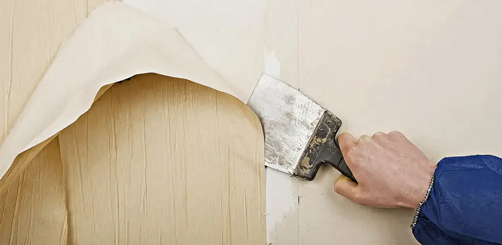 Handyman removing wallpaper with a scraper for wall preparation in Stockton, CA