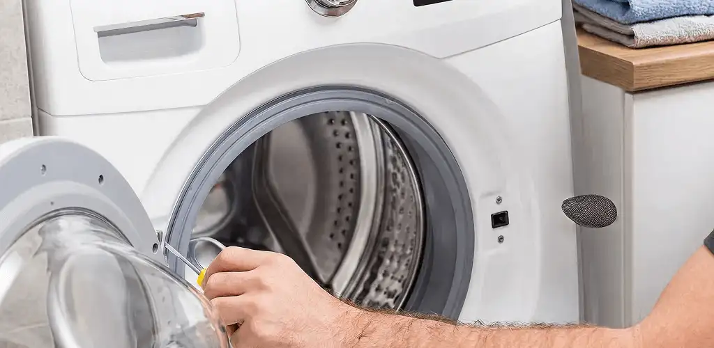 Handyman repairing a front-load washing machine and inspecting the drum in Stockton, CA